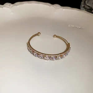 Detailed close-up of gold-tone double-layer bangle featuring sparkling water drop zircons
