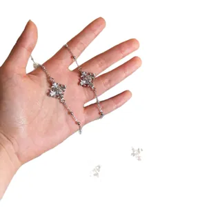 Elegant silver cross necklace with sparkling rhinestones held in hand for display.