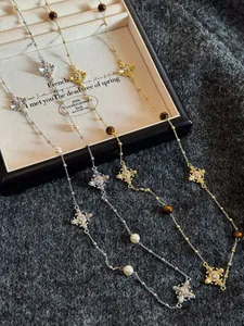 Macro detail of luxury cross pendant necklace with tiger eye stones and elegant pearls