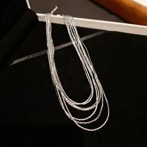 Close-up detail of multi-layered silver plated chain necklace on black velvet pad.