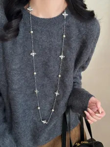 Elegant long cross and pearl sweater chain necklace styled on a grey knitted top