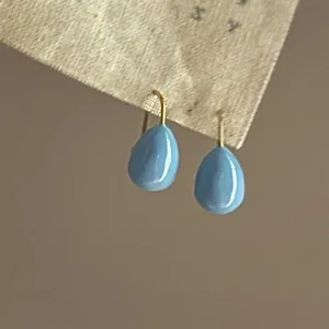 Detailed close-up view of light blue teardrop oil-drop earrings with gold ear hooks