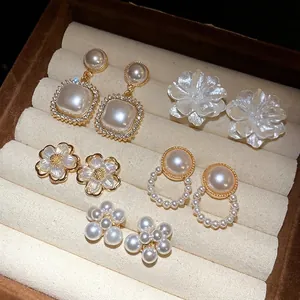 Collezione di cinque paia di orecchini vintage con perle e fiori in un vassoio di velluto