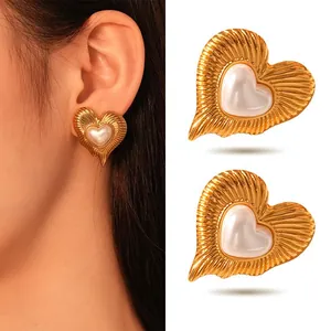 Vintage gold heart-shaped stud earrings with pearl inlay shown on model