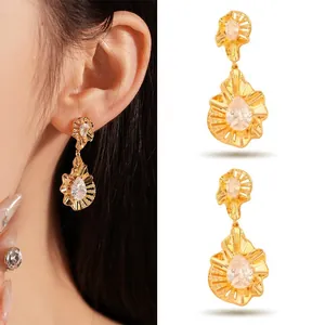 Detailed view of textured gold drop earrings with a central pear-cut crystal stone