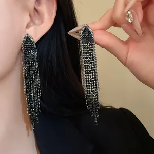 Detailed view of black rhinestone triangle tassel earrings worn on ear with sparkles