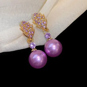 Close-up detail of elegant purple pearl earrings with rhinestone-encrusted leaf design.