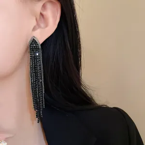 Exquisite close-up of long black tassel earrings with sparkling rhinestones worn by a model