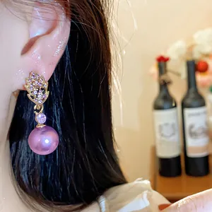 Close-up of elegant leaf-shaped earrings with purple rhinestones and pearls on ear