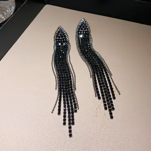 Detailed macro view of elegant black rhinestone tassel earrings with a silver finish.