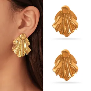 Close-up view of gold stainless steel rippled leaf earrings showing metallic texture and fit.