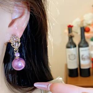 Close-up of elegant purple pearl earrings with leaf design on an Asian model's ear