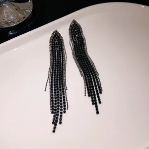 Detailed view of elegant black rhinestone triangle tassel earrings on white tray