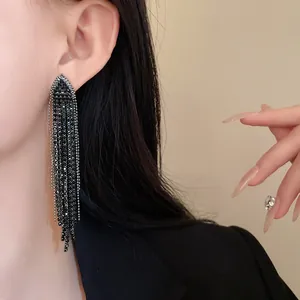 Detailed close-up of elegant black rhinestone triangle tassel earrings worn by a model