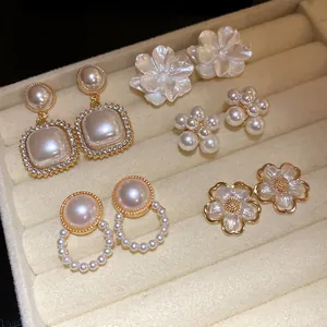 Dettaglio di un set di orecchini vintage con perle e fiori in un vassoio di velluto beige