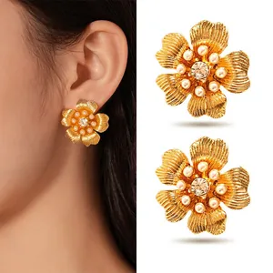 Detailed view of gold flower stud earrings with pearls and crystals on ear