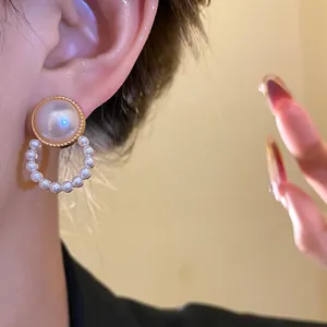 Dettaglio ravvicinato di orecchini vintage stile palazzo con perle e cerchio oro.