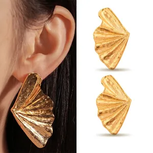 Close-up detail of oversized gold fan-shaped stainless steel stud earrings for women