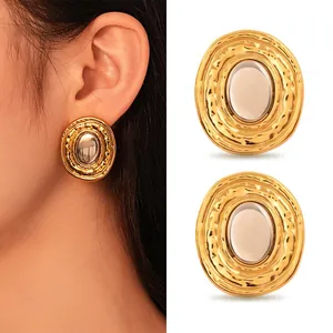 Detail view of chunky hammered gold oval earrings with smooth silver inlay on model