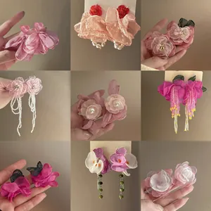 Close-up view of a collection of handmade pink fabric flower earrings with pearls and beads.