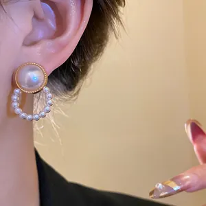 Primo piano di un elegante orecchino a bottone con perla in stile retrò indossato