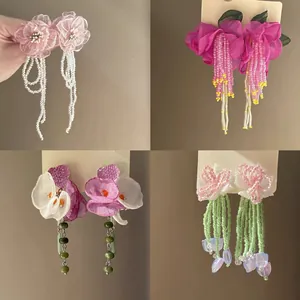 Detailed view of four unique handmade floral beaded tassel earrings in various colors.