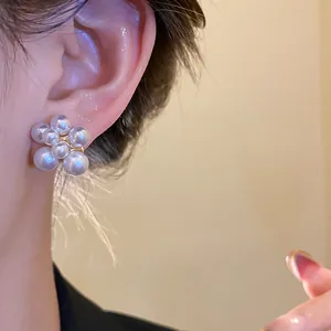 Primo piano di un orecchino a bottone a forma di fiore di perle con base dorata