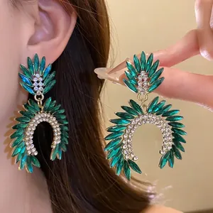 Detailed view of emerald green and clear crystal statement earrings with silver needles