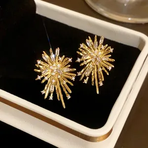 Detailed macro shot of golden firework earrings inlaid with sparkling white zircons