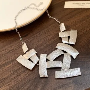 Detailed close-up of vintage silver textured geometric plate necklace on a wooden background