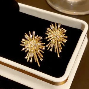 Close-up of sparkling zircon firework earrings with gold finish set in a black jewelry box
