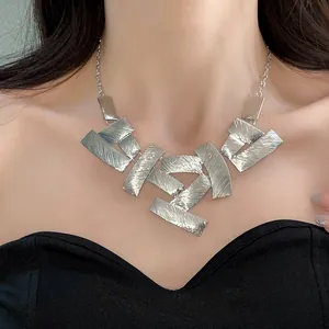 Close-up of a silver textured metal geometric patchwork necklace worn by a model