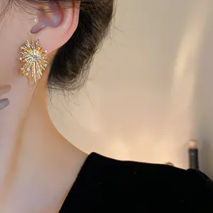 Close-up of a stylish gold firework stud earring with sparkling zirconia on a model's ear