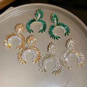 Close-up of elegant U-shaped rhinestone earrings in green, gold, and clear colors