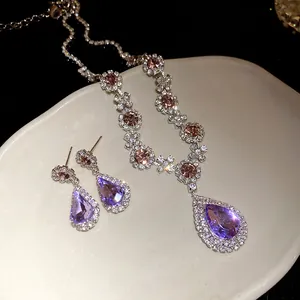 Detailed view of teardrop purple crystal necklace and earring set with rhinestones