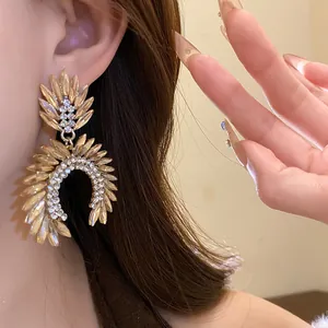 Detailed close-up of elegant gold leaf earrings with sparkling rhinestones on an ear.