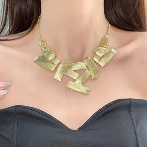 Detailed view of gold geometric textured plates on a vintage metal clavicle necklace.
