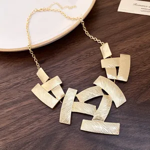 Detailed view of gold geometric textured metal plates on a minimalist necklace