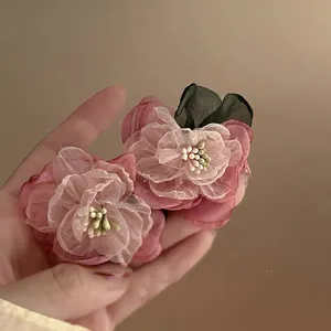 Detailed view of delicate pink organza flower earrings with pearl stamens