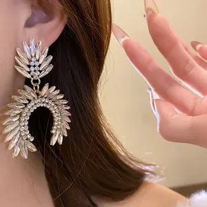 Detailed close-up showing the sparkling rhinestone dangle earrings on a model's ear.