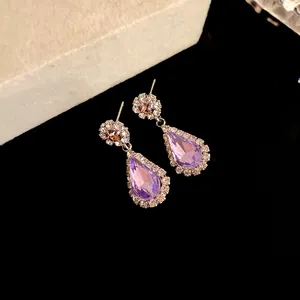 Close-up of elegant purple teardrop earrings with sparkling rhinestone halo