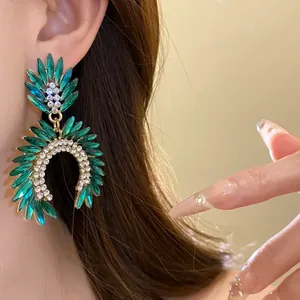 Detailed close-up of luxurious green crystal leaf earrings with sparkling rhinestones on model