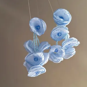 Close-up detail of elegant light blue organza flower earrings with beaded tassels