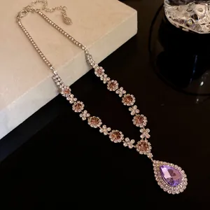 Close-up of an elegant necklace with a purple water-drop pendant and sparkling pink stones