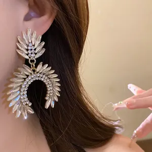 Close-up of elegant silver-toned rhinestone leaf-shaped dangling earrings on model