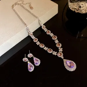 Detailed view of luxury silver-toned jewelry set featuring purple teardrop crystal pendant