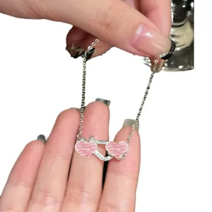 Elegant silver bracelet featuring a horseshoe buckle and two pink heart charms with zircons