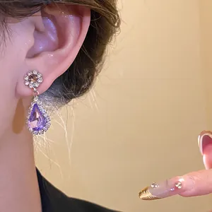 Close-up view of elegant purple waterdrop earrings with rhinestone halo on ear