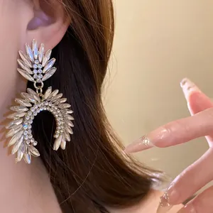 Close-up of elegant sparkling crystal drop earrings with leaf-like design on model