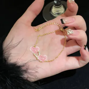 Detailed macro view of an elegant gold zircon bracelet with pink heart charms on hand
